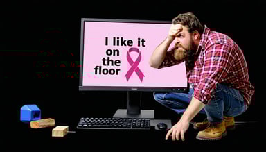 show a computer monitor with I like it on the floor with the cancer awareness logo with a confused lumberjack looking at it scratching his head